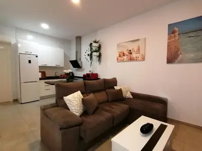 a living room with a brown couch and a kitchen at Apartamento Suite CALETA in Cádiz