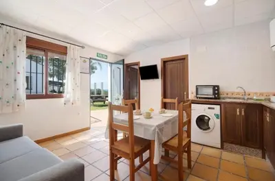 a kitchen and living room with a table and chairs at Novobarrosa Apartamentos Turísticos in Chiclana de la Frontera