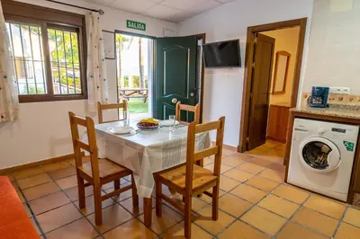 a kitchen with a table and chairs and a washing machine at Novobarrosa Apartamentos Turísticos in Chiclana de la Frontera