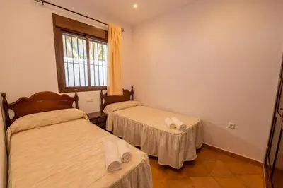 a room with two beds and a window at Novobarrosa Apartamentos Turísticos in Chiclana de la Frontera