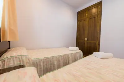 a room with two beds and a cabinet in it at Novobarrosa Apartamentos Turísticos in Chiclana de la Frontera