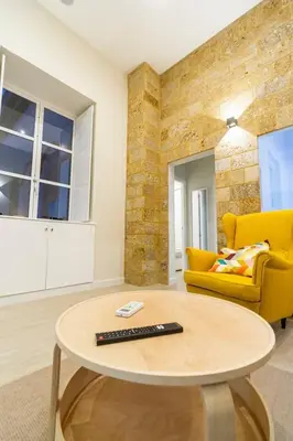 a living room with a table and a yellow couch at SH Casa Candelaria. Apartamento en el centro. in Cádiz