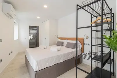 a bedroom with a large bed and a black rack at Allo Apartments San Roque Bajo B in Cádiz