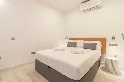 a white bedroom with a large bed with white sheets at Allo Apartments San Roque Bajo C in Cádiz