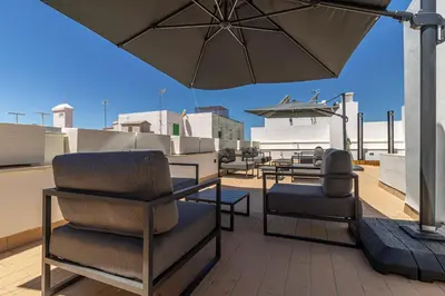 a patio with chairs and an umbrella on a roof at Allo Apartments San Roque 1ºB in Cádiz