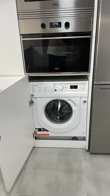 a kitchen with a microwave and a washing machine at Piso de lujo en primera linea de playa y garaje in Cádiz