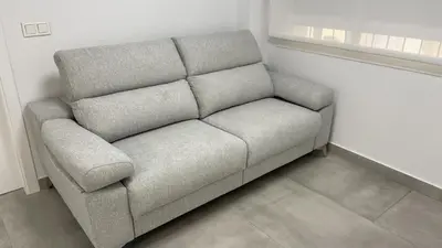 a gray couch sitting in a corner of a room at Piso de lujo en primera linea de playa y garaje in Cádiz