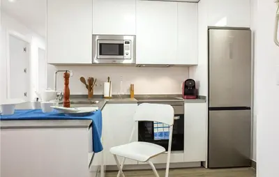 a kitchen with white cabinets and a white chair at 3 Bedroom Amazing Apartment In Cadiz in Cádiz