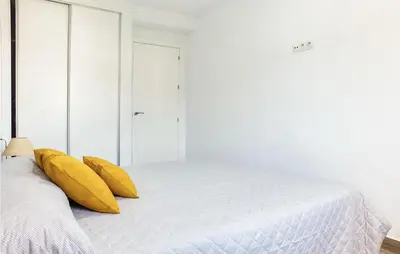 a white bedroom with yellow pillows on a bed at 3 Bedroom Amazing Apartment In Cadiz in Cádiz
