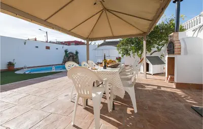 a table and chairs under an umbrella on a patio at Stunning Home In San Jose Del Valle in San Jose del Valle