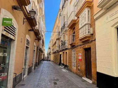 an empty street in an alley between buildings at La Casita del Arte in Cádiz