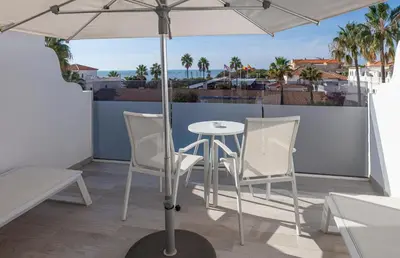 a table and chairs on a balcony with an umbrella at Playa de la Luz in Rota