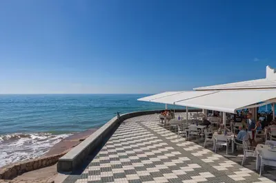 a pier with tables and chairs and the ocean at Playa de la Luz in Rota
