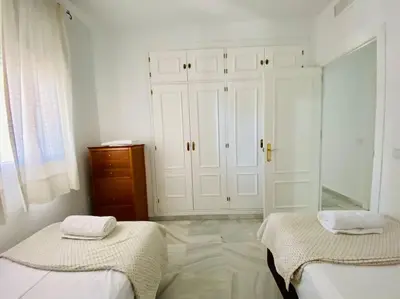 a white room with two beds and a dresser at Villa palacio Playa y piscina Grupo AC Gestion in Cádiz