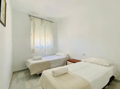 two beds in a white room with a window at Villa palacio Playa y piscina Grupo AC Gestion in Cádiz
