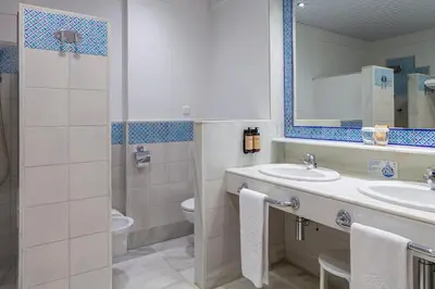 a bathroom with a sink and a toilet and a mirror at Hotel Duque de Najera in Rota