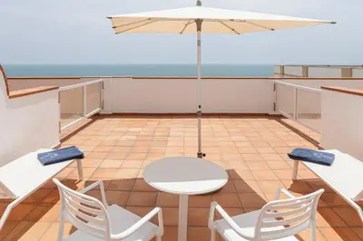 a balcony with a table and chairs and an umbrella at Hotel Duque de Najera in Rota