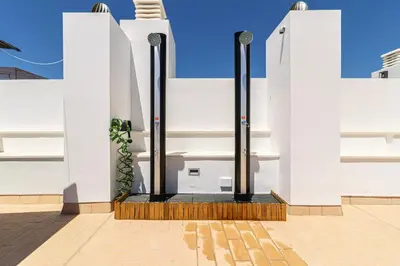 a white building with black poles and a plant at Allo Apartments San Roque 1ºC in Cádiz