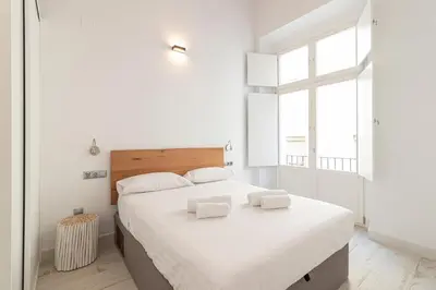 a white bedroom with a large bed and a window at Allo Apartments San Roque 2ºA in Cádiz