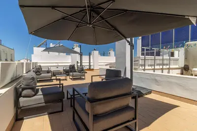 a patio with chairs and an umbrella on a roof at Allo Apartments San Roque 2ºB in Cádiz