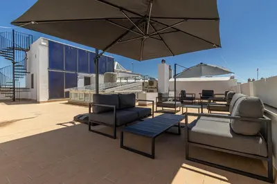 a patio with chairs and tables and an umbrella at Allo Apartments San Roque 2ºB in Cádiz
