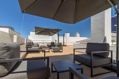 a patio with chairs and tables and an umbrella at Allo Apartments San Roque 3ºA in Cádiz