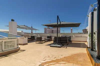 a patio with chairs and an umbrella on a roof at Allo Apartments San Roque 3ºA in Cádiz