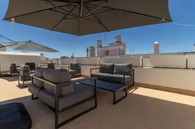 a patio with chairs and an umbrella on a roof at Allo Apartments San Roque 3ºB in Cádiz