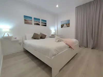 a white bedroom with a large bed and a window at Apartamento Catamarán in El Puerto de Santa María