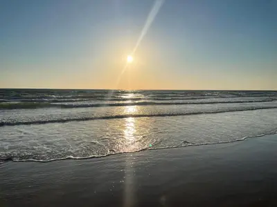 a beach with the sun rising over the ocean at Apartamento en Costa Ballena in Chipiona