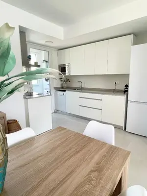 a kitchen with white cabinets and a wooden table at Apartamento en Costa Ballena in Chipiona