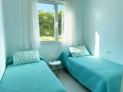 a blue bedroom with two beds and a window at Apartamento en Costa Ballena in Chipiona