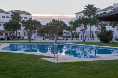 a swimming pool in a yard with trees and houses at Precioso apartamento a 700 m del mar in Chiclana de la Frontera