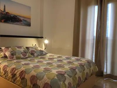 a bed with a colorful comforter in a bedroom at Precioso apartamento a 700 m del mar in Chiclana de la Frontera