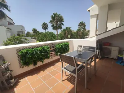 a patio with a table and chairs on a balcony at Precioso apartamento a 700 m del mar in Chiclana de la Frontera