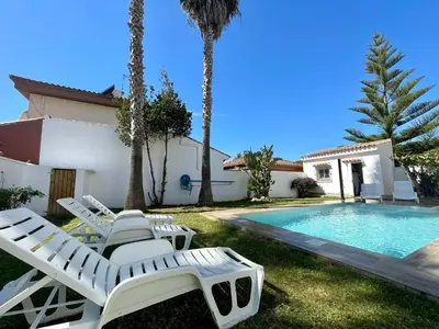 a villa with a swimming pool and lounge chairs at Chalet Edén Azul in Chiclana de la Frontera