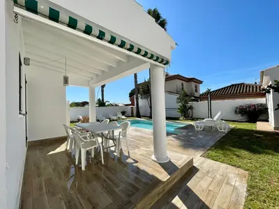a patio with a table and chairs and a pool at Chalet Edén Azul in Chiclana de la Frontera