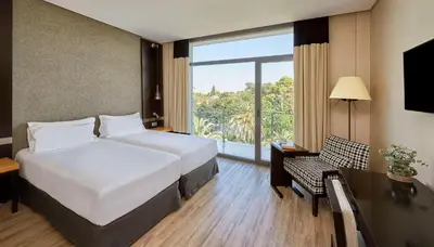 a hotel room with two beds and a window at NH Avenida Jerez in Jerez de la Frontera