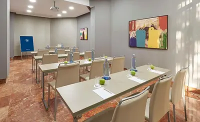 a room with tables and chairs and a painting on the wall at NH Avenida Jerez in Jerez de la Frontera