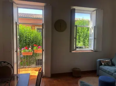 a living room with two windows and a table and a couch at Gran casa con balcón para grupos en centro histórico in El Puerto de Santa María