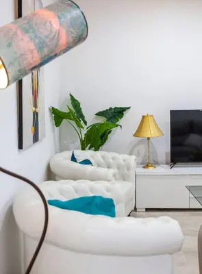three white chairs in a living room with a lamp at SH Piluca's Home. Moderno apartamento con patio in Cádiz