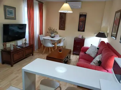 a living room with a red couch and a tv at Apartamento la Concha in Chiclana de la Frontera