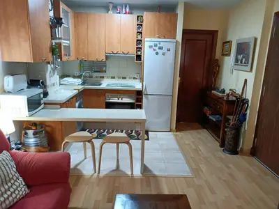 a kitchen with a table and a white refrigerator at Apartamento la Concha in Chiclana de la Frontera