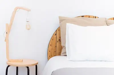 a white bed with a wooden headboard and a stool at La Casa Morada in Cádiz