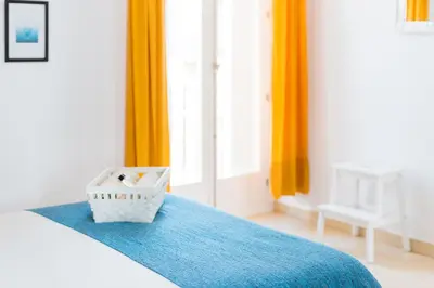 a bedroom with orange curtains and a bed with a basket at La Casa Morada in Cádiz