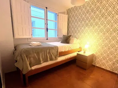 a small bedroom with a bed with a window at Apartamento La Laja 5 min de la playa in Cádiz