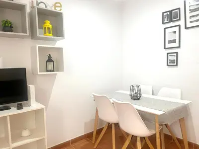a dining room with a white table and white chairs at Apartamento La Laja 5 min de la playa in Cádiz