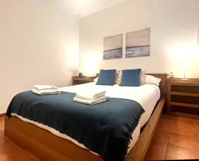 a bedroom with a large bed with blue pillows at Apartamento La Laja 5 min de la playa in Cádiz