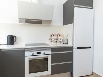 a kitchen with white chairs and a table and a counter at GuestReady - Blanca Paloma Ana in El Puerto de Santa María