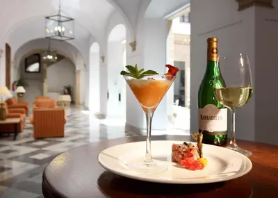 a drink on a plate next to a bottle of wine at Crisol Monasterio de San Miguel in El Puerto de Santa María